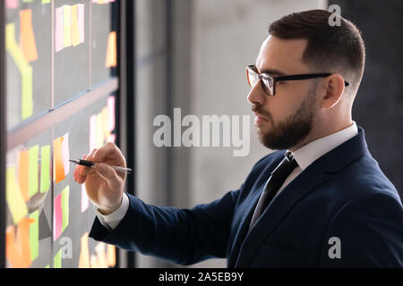 Serious businessman wear suit writing business ideas on sticky notes Stock Photo