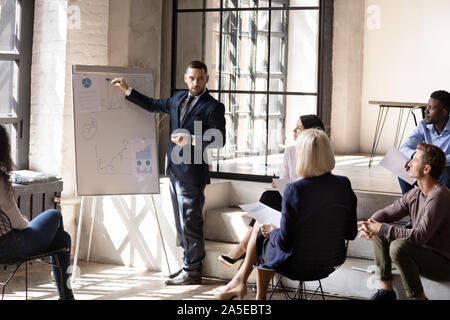 Serious male speaker give business presentation drawing on flip chart Stock Photo