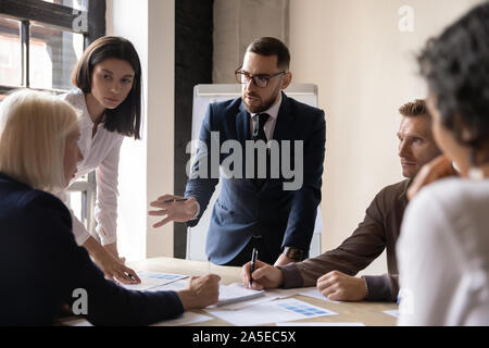 Serious busy designers team brainstorming on paperwork discussing ideas Stock Photo
