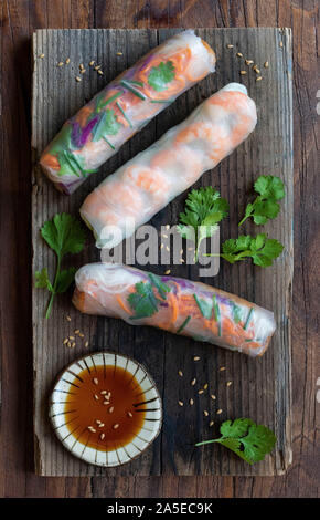 Colorful Vietnamese spring rolls on wooden board with dipping sauce in natural light Stock Photo