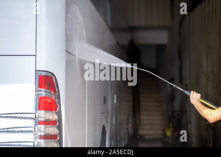 bus get washed from a washer with water jet in garage. Stock Photo