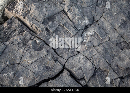 A large rock is fractured, with cracks forming interesting fragments and interesting texture. Stock Photo