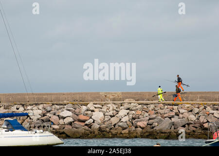 Sea anglers on their way to go fishing on Brixham Breakwater near the town of Brixham in Devon England UK GB Stock Photo