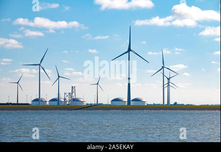 Contrast of an old and new source of energy: Wind turbines and oil storage tanks at the Eemshaven seaport in Groningen, Netherlands Stock Photo