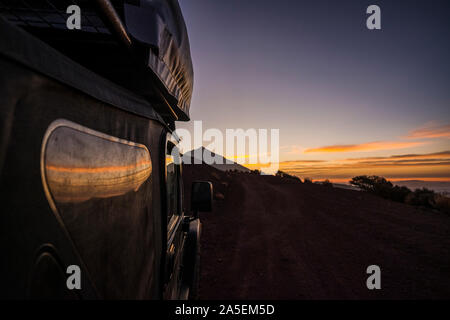 Close up of black of roas adventure car parked with beautiful sunset and mountain in background - concept of travel and discover wild places and enjoy Stock Photo