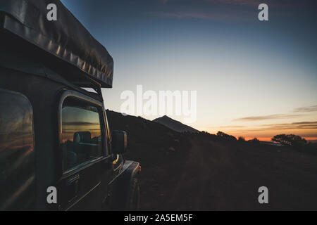 Close up of black of roas adventure car parked with beautiful sunset and mountain in background - concept of travel and discover wild places and enjoy Stock Photo