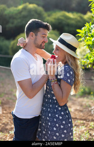 Young couple in love eating strawberry in picnic outside Stock Photo