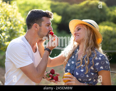 Happy young vivacious Caucasian couple joking on picnic in nature Stock Photo