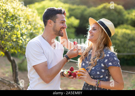 Happy young vivacious Caucasian couple laughing on picnic in nature Stock Photo