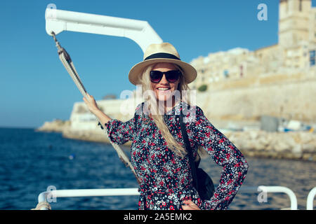 Happy young 20s blonde traveler woman arriving to destination on Mediterranean sea Stock Photo