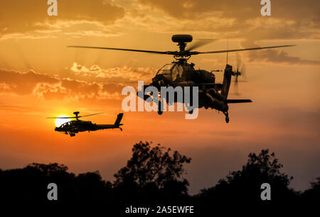 Two Agusta Westland AH-1 / AH-64 Apache Longbow gunship helicopters silhouetted at sunset Stock Photo