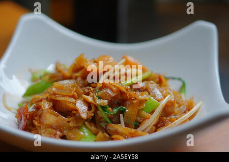 Penang Char Kway Teow or Char Koay Teow (stir-fried rice cake strips / fried flat noodles) in white plate at Southeast Asia cuisine restaurant Stock Photo