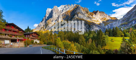 Grindelwald, Switzerland street and autumn Swiss Alps mountains panorama landscape, wooden chalets on green fields and high peaks in background, Berne Stock Photo