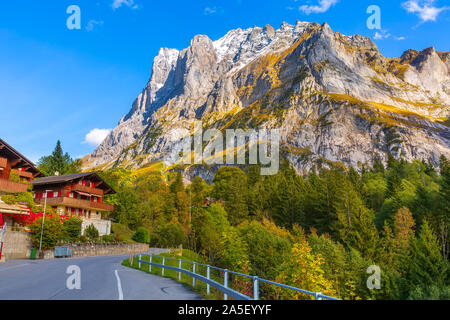 Grindelwald, Switzerland street and autumn Swiss Alps mountains panorama landscape, wooden chalets on green fields and high peaks in background, Berne Stock Photo