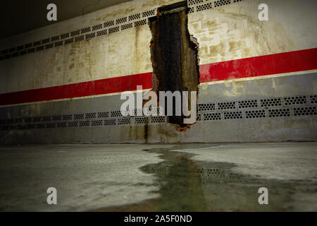 Cambre / Spain - October 20 2019: Water pooling from black slime oozing from a hole in an underground basement wall Stock Photo