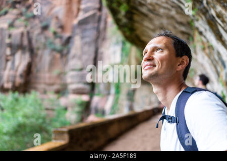 Zion National Park in Utah with happy hiker man standing under weeping rock trail waterfall and formations in summer Stock Photo