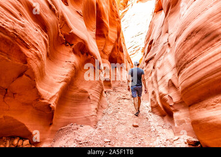 Man hiker walking by red wave shape formations at Antelope slot canyon in Arizona on footpath trail from Lake Powell