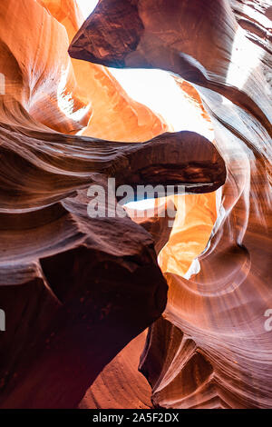 Low angle vertical view of upper Antelope slot canyon with bright sky abstract formations of red orange rock layers sandstone in Page, Arizona Stock Photo