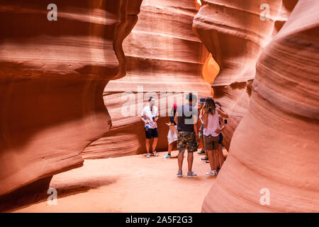 Page, USA - August 10, 2019: Navajo tribal tours people group at Upper Antelope slot canyon in Arizona walking on narrow trail footpath Stock Photo