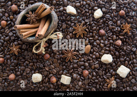 Christmas coffee beans background. Decorative jug with cinnamon sticks, almonds, anise and cane sugar. Top view. Stock Photo