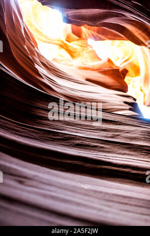 Closeup of texture and vertical view of light sky at upper Antelope slot canyon with red layers of wave shape rock sandstone in Page, Arizona Stock Photo