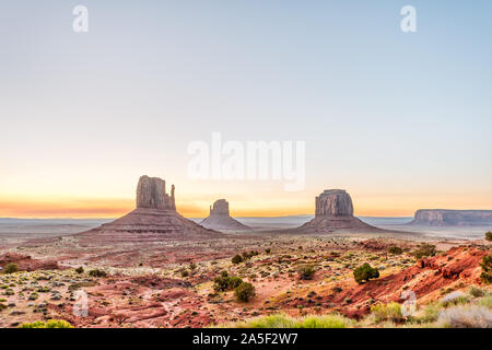 Wide angle view of buttes and horizon in Monument Valley at sunrise colorful light in Arizona with orange rocks Stock Photo