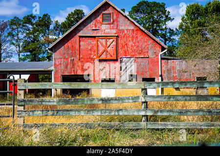 Abandoned weathered and worn old red barn with split-rail fence. Stock Photo