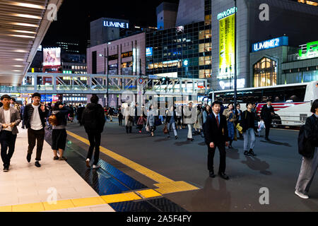 Shinjuku, Japan - March 28, 2019: Large shopping center in downtown Tokyo city with many Japanese workers people on street outside station after work Stock Photo