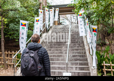 Tokyo, Japan - March 28, 2019: Famous Togo shrine temple steps up entrance with back of tourist man standing on street in Shibuya Harajuku Stock Photo