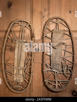 Closeup of a pair of very old snowshoes hanging on a wooden wall Stock Photo