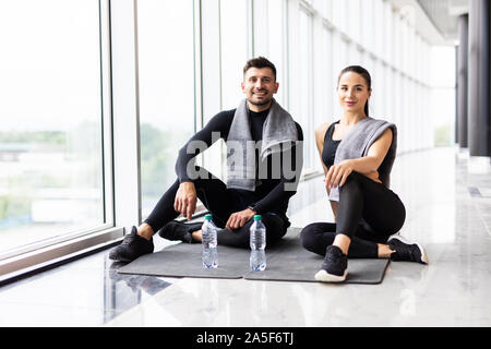 Young healthy couple relaxing after workout in the gym with happy facial expressions. Stock Photo