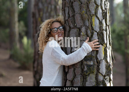 one woman hugging with close eyes a old tree on the forest - love and affection at the wood - save the forest and climate change concept - respect nat Stock Photo