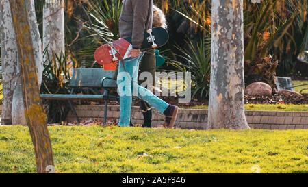 Unrecognizable skaters couple walking in the park, in autumn. Stock Photo