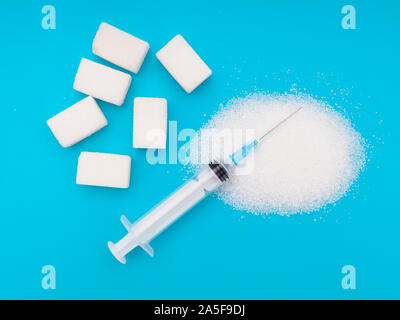 White sugar, cubes and granulated, on bright colourful background with syringe. Unhealthy eating, diabetes health risks etc. Stock Photo