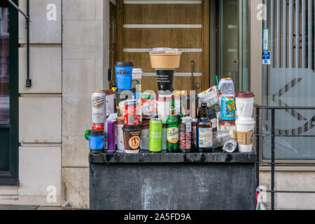 Rubbish balanced on street furniture after protest demonstration in central London. Takeaway coffee cups, beer cans & bottles & fast food containers. Stock Photo