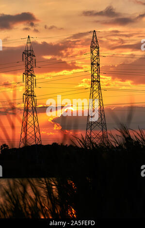 Silhouetted electricity pylons with the vivid sky of sunset Stock Photo ...
