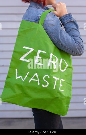 Green textile eco bag with the inscription zero waste on the girl’s shoulder. The bag is empty. Stock Photo