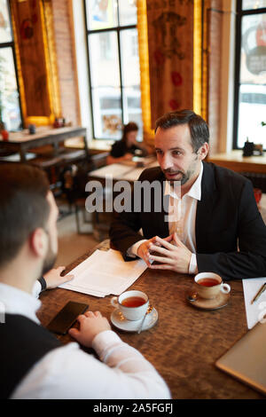 High angle view of two successful businessmen discussing deal while sitting at table in luxurious cafe, copy space Stock Photo