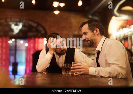 Portrait of two drunk business people talking sitting at table in bar after work, copy space Stock Photo