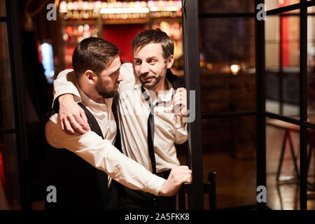 Portrait of wo drunk business men leaving bar late night after work, copy space Stock Photo