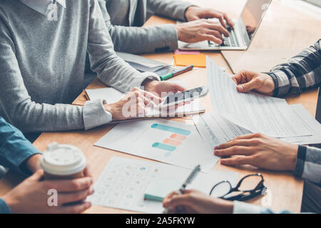 Startupers working together at office having business meeting table close-up looking at documents drinking coffee browsing devices Stock Photo