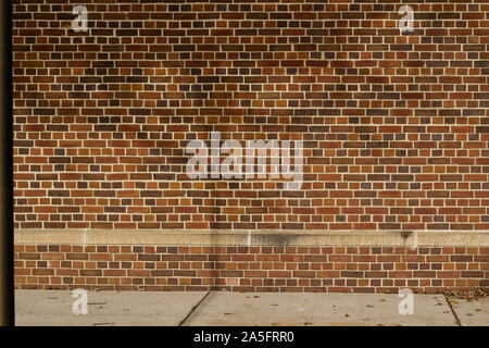 Reddish brown brick wall texture with English bond brickwork pattern, showing shadows from trees and a street light Stock Photo