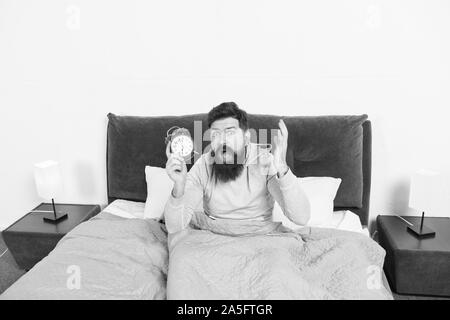 Tips for waking up early. Man bearded hipster sleepy face waking up. Daily schedule for healthy lifestyle. Again unhappy in morning. Alarm clock ringing. Problem early morning awakening. Get up early. Stock Photo