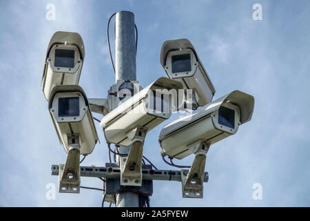 Low angle frontal view of multiple outdoor CCTV surveillance cameras on a steel pole against a sky, monitoring public space Germany Stock Photo