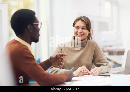 Portrait of beautiful young woman smiling happily while enjoying class in college and talking to African-American classmate, copy space Stock Photo