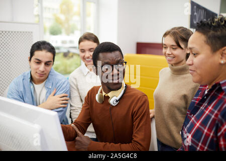 Portrait of multi-ethnic group of students using computer while researching for team project in library Stock Photo