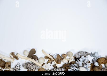 Overhead shot of a white surface with pine cones in the bottom great for writing holiday text Stock Photo