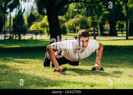 Fitness gym push up exercise man doing shoulder press workout for training muscles outdoor on meadow in the park Stock Photo
