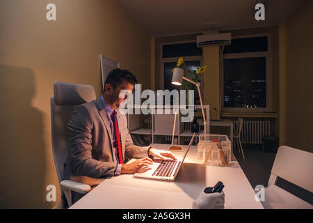 Serious doctor working on his laptop ( pc ) at night, overtime. Stock Photo