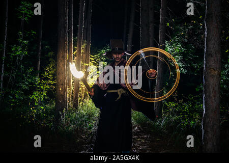 Fantasy wizard making magical circle speells with his pendulum in the woods during midnight Stock Photo